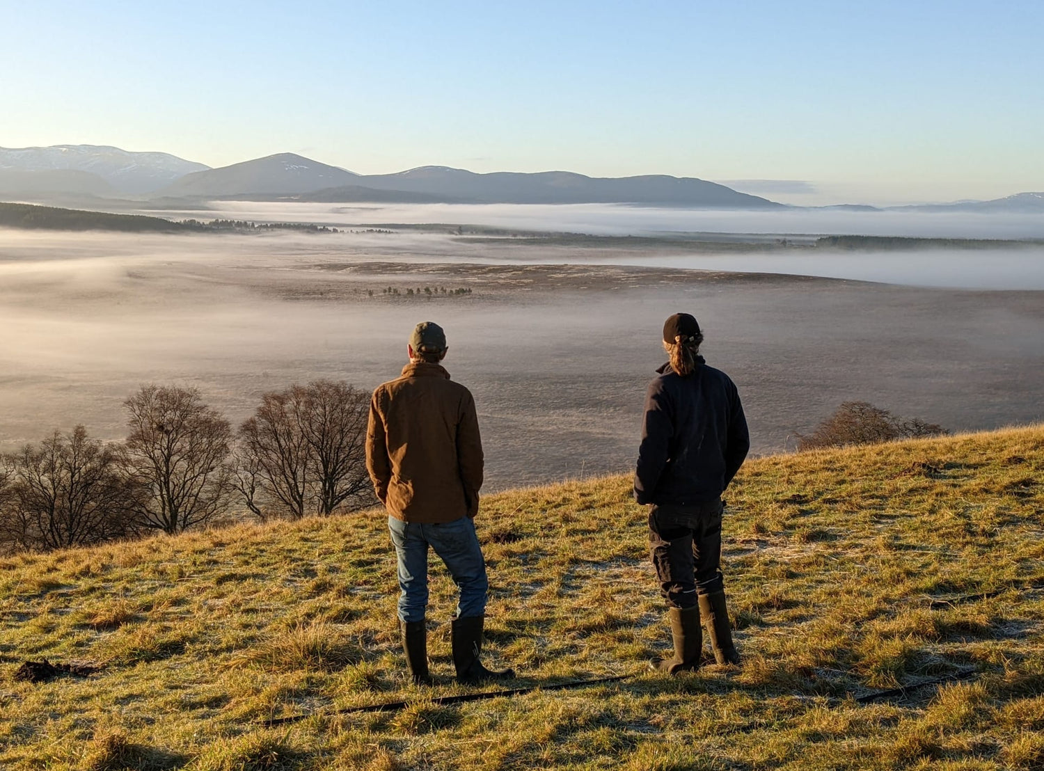 Two people admiring a cloud inversion at the feet of the Cairngorms mountains.